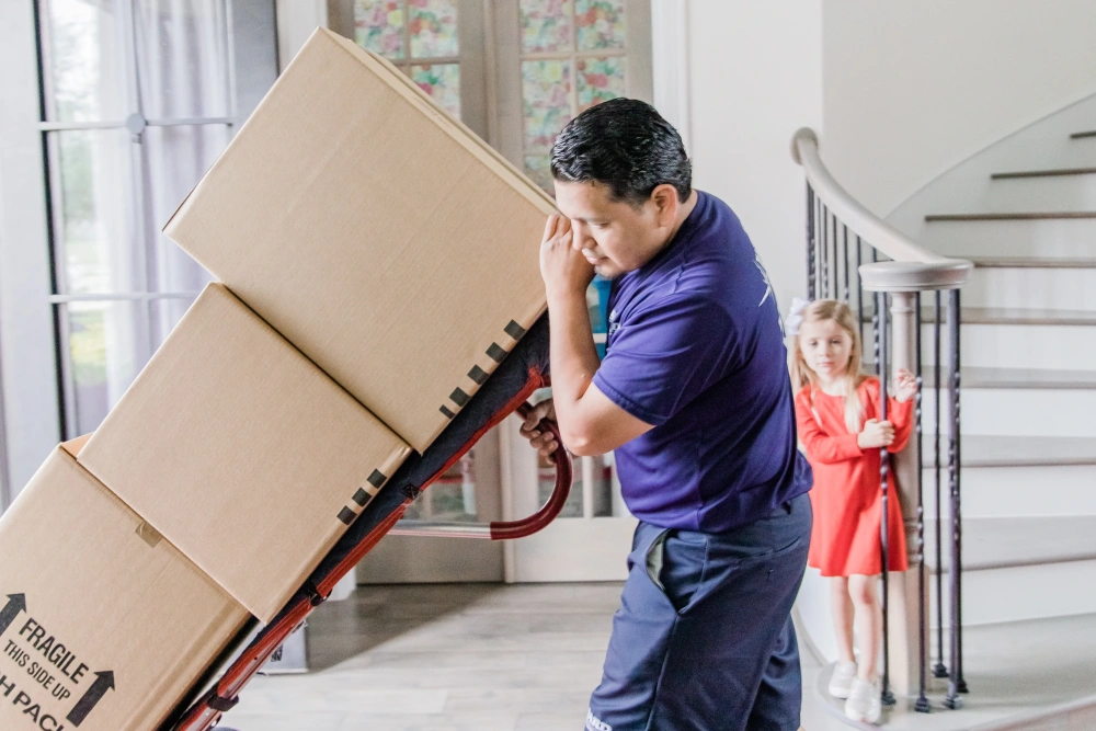 Man rolling boxes out of house on a cart